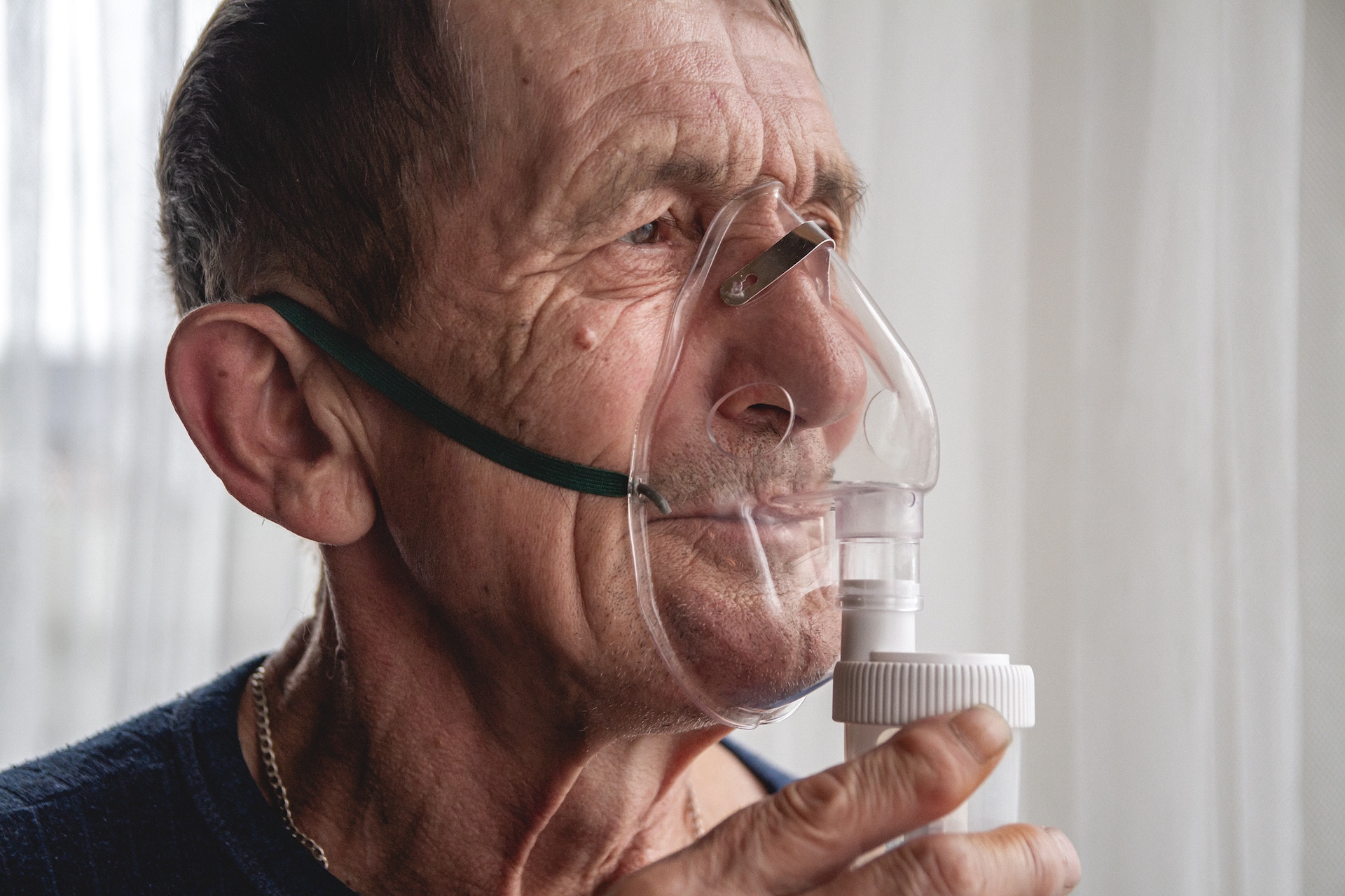 An elderly person wearing an oxygen mask in quarantine