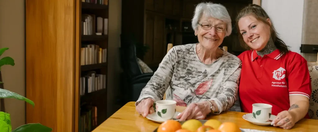 Seniorin und Haushaltshilfe trinken gemeinsam Kaffee