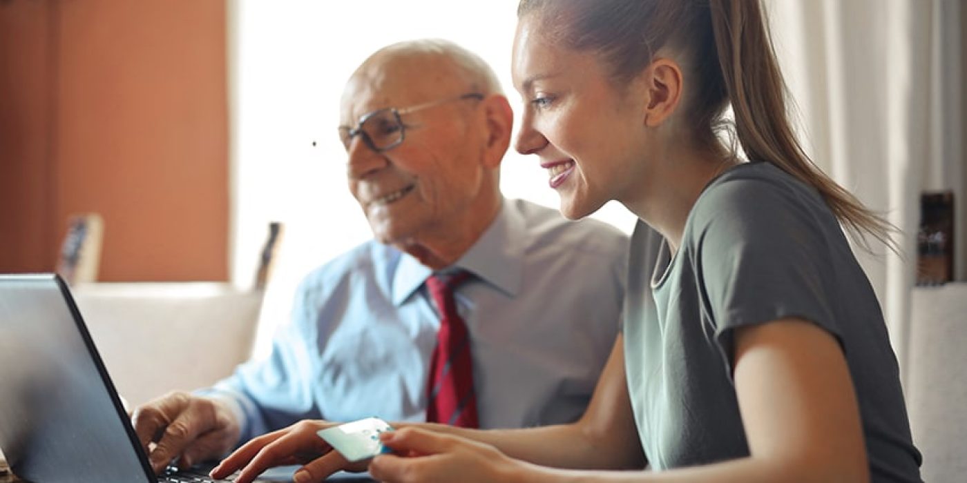 Canva - Young woman helping senior man with payment on Internet using laptop 72dpi