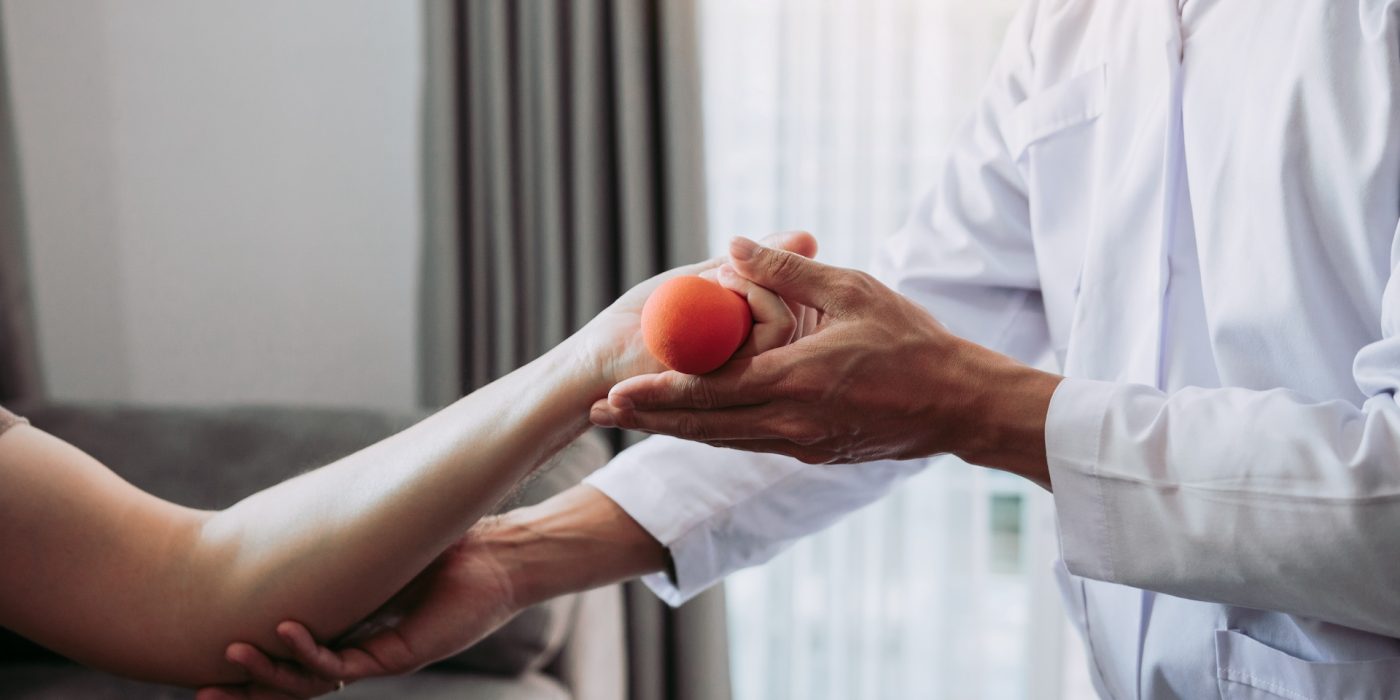 asian young male physiotherapist helping patient with lifting dumbbells exercises in office.
