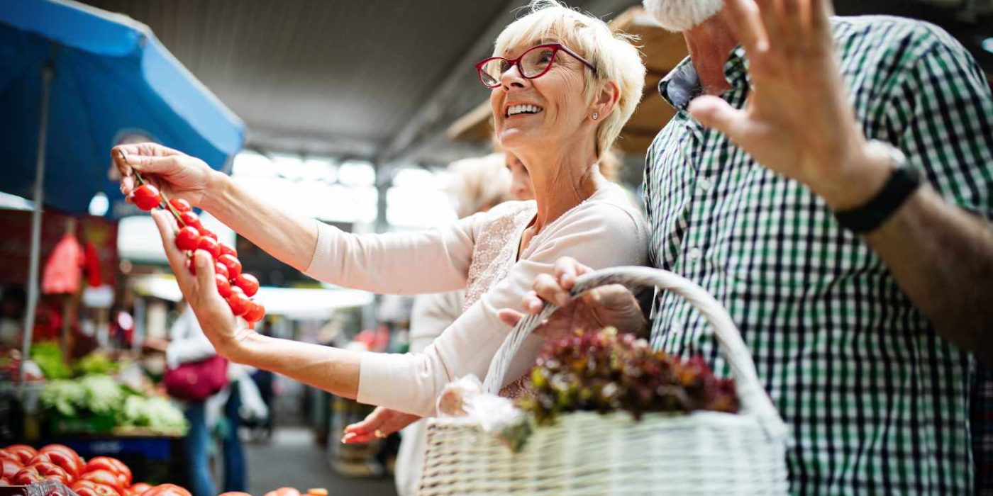 Senior happy shopping couple with basket on the market. Healthy diet.