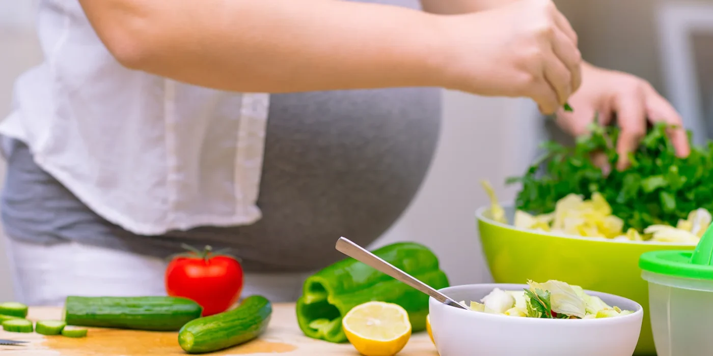 schwangere bereitet salat zu