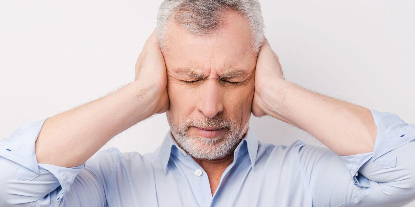 Tinnitus: Mann hält sich die Ohren zu, weil der Tinnitus zu laut ist