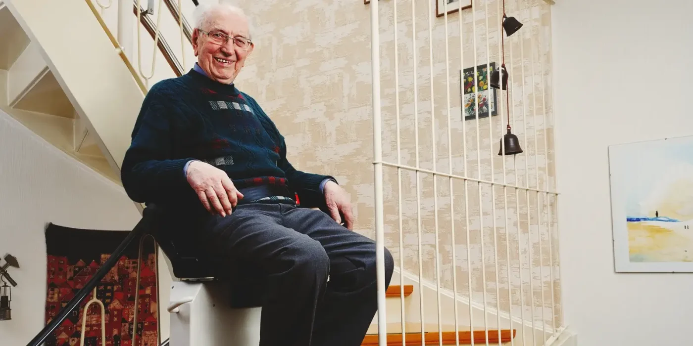 Senior sitzt auf seinem Treppenlift | Zuschuss für wohnumfeldverbessernde Maßnahmen